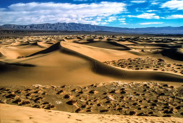 Landscape with sand dunes in the foreground and mountains in the background